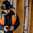 Construction workers looks at phone on job site