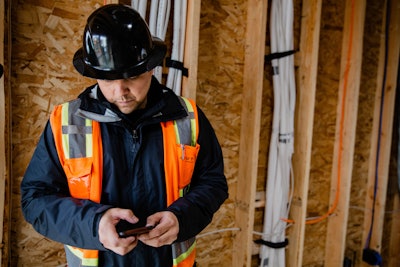 Construction workers looks at phone on job site