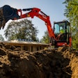 Kubota KX030-4 compact excavator behind dirt trench bucket raised to side