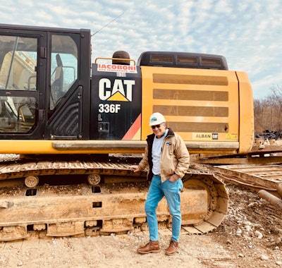 Tom Iacoboni owner Iacoboni Site Specialists leaning on track of Cat 336F excavator in hardhat jeans