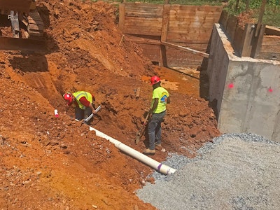 Iacoboni Site Specialists 2 workers laying pipe in red clay trench