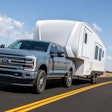 2023 Ford Super F-350 Limited blue-gray pickup truck pulling white camper on desert highway