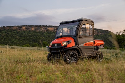 2023 Kubota RTV520 in grassy field with brush covered hill in background