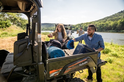 2023 Kubota Sidekick UTV black cargo area man woman remove items lake in background