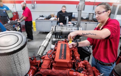 Female diesel tech at UTI working on Cummins engine