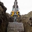 Backhoe digging trench in dirt stock image