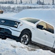 white Ford F-150 Lightning driving up snow bank