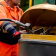 stock image worker in orange outfit pumping diesel into construction equipment tank