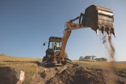 New Holland 875D backhoe bucket raised after dumping dirt in hole