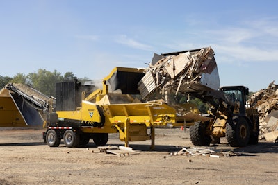 Vermeer HG4000 horizontal grinder on trailer being loaded with wood debris by wheel loader