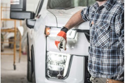 cover Equipment World 2023 Contractors' Pickup Truck Guide worker in yellow hard hat with elbow leaning against front of white pickup