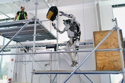 Boston Dynamics humanoid robot Atlas tosses a tool bag to a worker on a scaffold