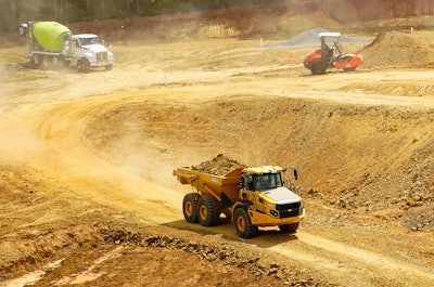 Bell B30E articulated dump truck carrying dirt load on dirt paving site