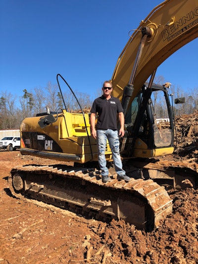 Todd Bennick standing on tracks of Caterpillar excavator