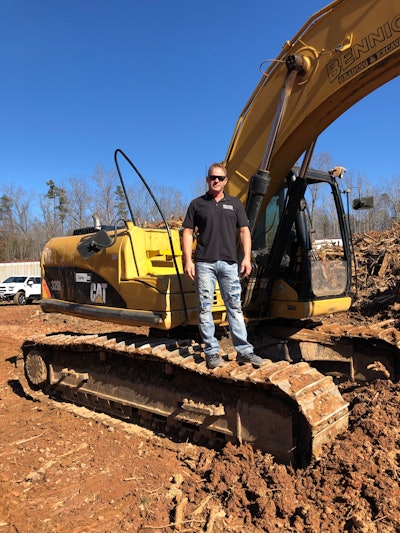 Todd Bennick standing on tracks of Caterpillar excavator