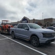 Ford F-150 Lightning with trailer hauling Kubota tractor in Lowe's parking lot
