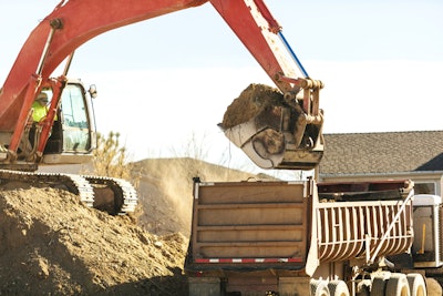 excavator dumping scoop of dirt into dump truck body