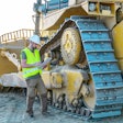 Worker standing by large dozer.