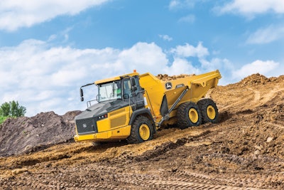 John Deere 310E articulated dump truck driving down dirt hill with load of dirt