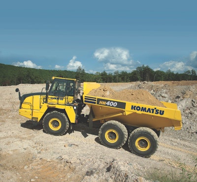 Komatsu HM400 articulated dump truck loaded with dirt on quarry road incline