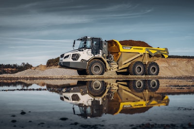 Liebherr TA230 articulated dump truck loaded with dirt in front of large puddle