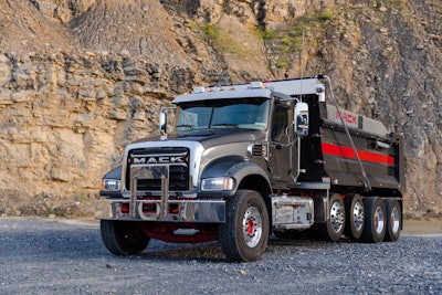 black refreshed Mack Granite dump truck in front of quarry wall