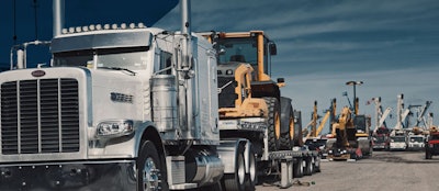 Semi hauling a piece of heavy equipment from an auction yard