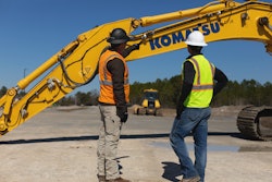 Workers looking over boom of Komatsu smart construction retrofit.