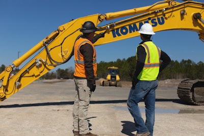 Workers looking over boom of Komatsu smart construction retrofit.