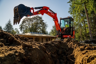 Kubota KX030-4 compact excavator digging trench behind house