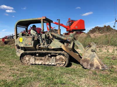 1972 Case Marine Corps 1150 track loader on grassy field in front of red antique crawler crane