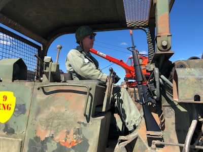 Jim Carter in military fatigues and helmet inside Case MC 1150 track loader