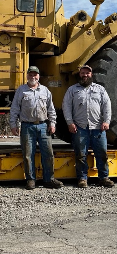 Alan and George Marsh posing in front of vintage construction equipment
