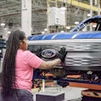female worker places Ford emblem on grille of Ford F-150 Lightning at factory