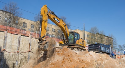 Sany SY335C LC excavator on dirt hill in front of concrete wall digging