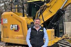 Shay Stutsman equipment world contractor of the year in front of Cat excavator in Aspen Colorado