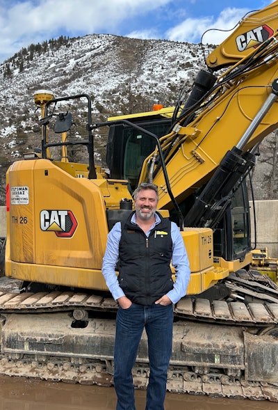 Shay Stutsman equipment world contractor of the year in front of Cat excavator in Aspen Colorado
