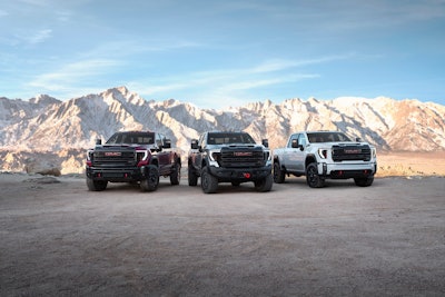 3 2024 GMC Sierra 2500 HD pickup trucks facing camera with mountains background