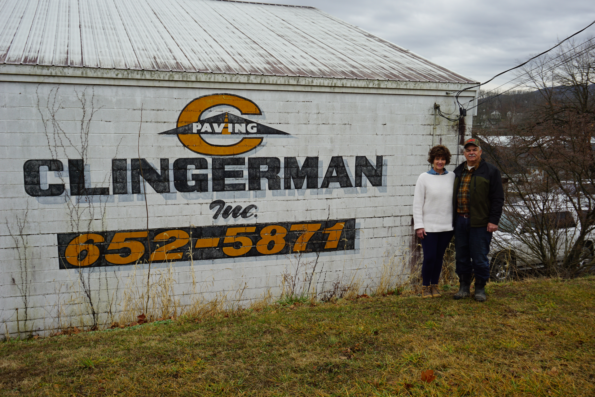 Kenny and Paula Clingerman beside white building with Clingerman Inc logo company name and photo number