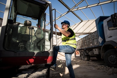 Operator climbing into the cab of an excavator