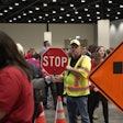 worker in yellow vest holds stop sign at teen work zone safety event oklahoma
