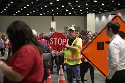worker in yellow vest holds stop sign at teen work zone safety event oklahoma