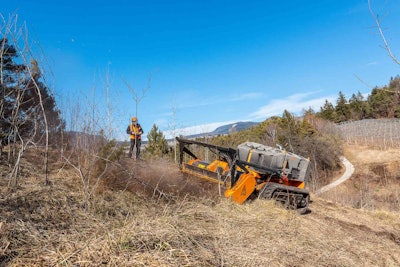 FAE RCU-55 cutting through brush on slope worker in orange hardhat and vest operates by remote control