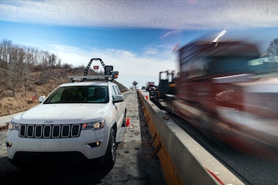 Jeep SUV with automated speed camera beside busy highway work zone