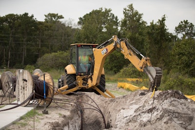 Cat 420XE backhoe digging fiber optic wire trench stabilizers out