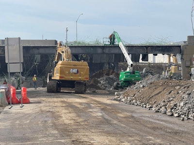 Cat excavator green white telehandler work on demolition of collapsed I-95 overpass Philadelphia