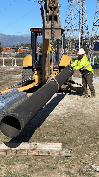 McKinney Construction crew moving pipe with backhoe