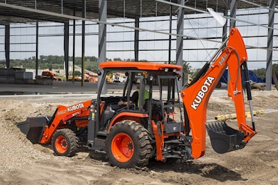 Kubota M62 backhoe filling front loader with dirt at under construction building