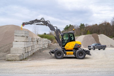 Mecalac 11MWR wheeled excavator lifting concrete blocks