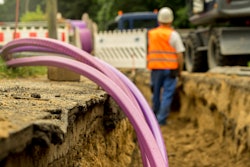 purple conduit for fiber optic line in trench with worker background